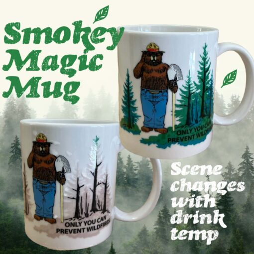 Image of the "Smokey Magic Mug" featuring Smokey Bear holding a shovel with the message "Only You Can Prevent Wildfires." The mug has a color-changing design that reveals two different scenes based on the drink temperature: a burned, charred forest when the mug is cool and a lush, green forest when the mug is warm. Text on the image reads "Smokey Magic Mug" and "Scene changes with drink temp." The background has a forested setting, enhancing the theme of forest conservation.