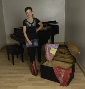 Photo of a woman standing next to a piano with red cowboy boots