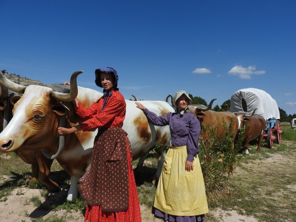Living history interns in period outfits near fiberglass oxen at Scotts Bluff National Monument. 