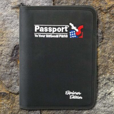 Park passport explorers edition front cover on a natural rock surface. Fabric cover with zipper end in upper left.