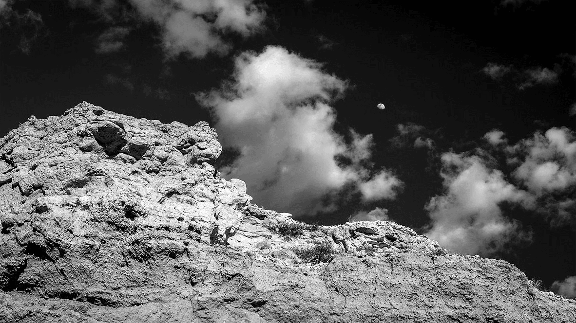 John Emery's black-and-white photograph of a rocky formation beneath clouds and the moon