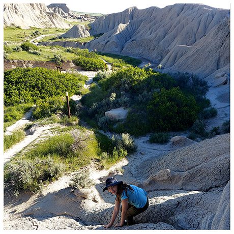 Young girl climbing on sandstone hillside above trail