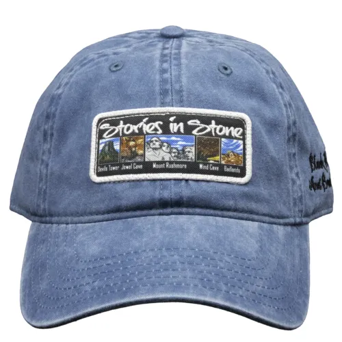 Front view of a denim blue Stories in Stone baseball cap with an embroidered patch showing colorful scenes of Devils Tower, Jewel Cave, Mount Rushmore, Wind Cave, and Badlands, with “Stories in Stone” stitched across the top.