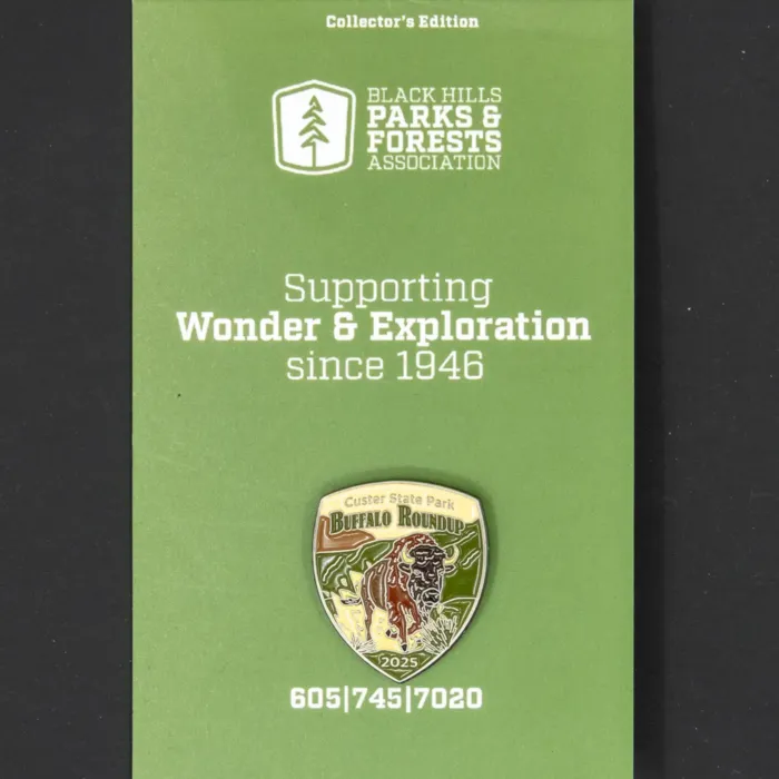 The 2025 Buffalo Roundup pin mounted on its green collector's edition backing card. The card features the Black Hills Parks & Forests Association logo and tagline: "Supporting Wonder & Exploration since 1946."