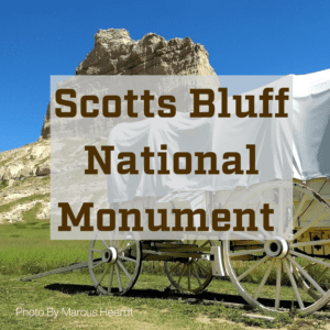 A picture with a historic wagon used on the Oregon Trail in front of Scotts Bluff Monument With the text Scotts Bluff National Monument