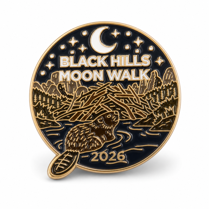 Round enamel lapel pin with a navy blue background and gold artwork. A beaver swims across water beneath a crescent moon and stars, with a Black Hills ridgeline and pine trees behind it. The pin reads Black Hills Moon Walk above the scene and is dated 2026 at the bottom.