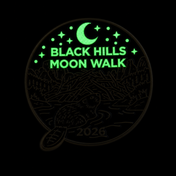 The pin shown in darkness. The crescent moon, stars, and the words Black Hills Moon Walk glow pale green, with the rest of the design faintly outlined.
