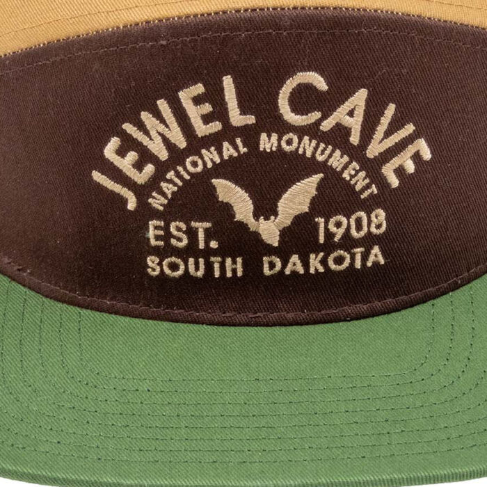 Close-up of the cream embroidery: Jewel Cave National Monument arched over a bat, EST. 1908, South Dakota