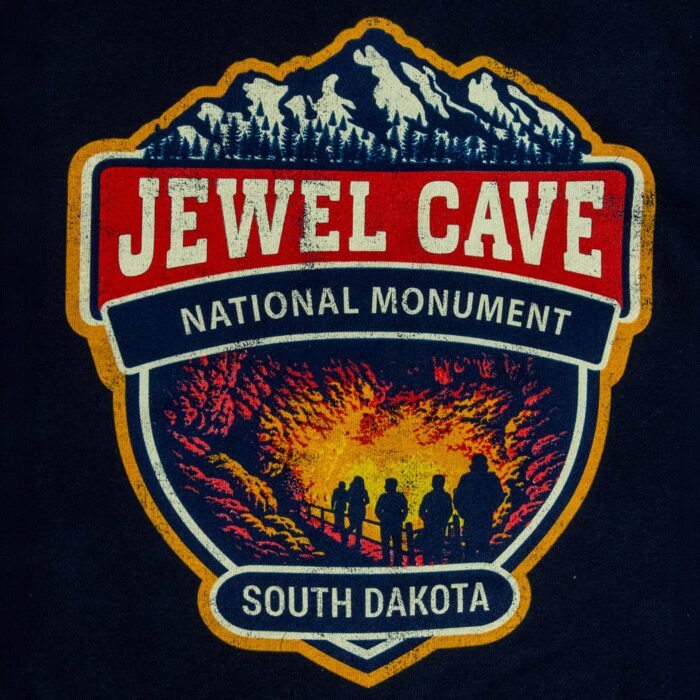 Close-up of the Jewel Cave National Monument back graphic, five visitors in silhouette on a lit cave walkway