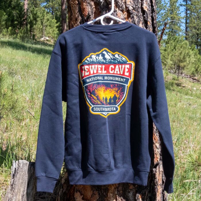 Navy Jewel Cave National Monument sweatshirt outdoors in the Black Hills, showing the back cave-tour badge