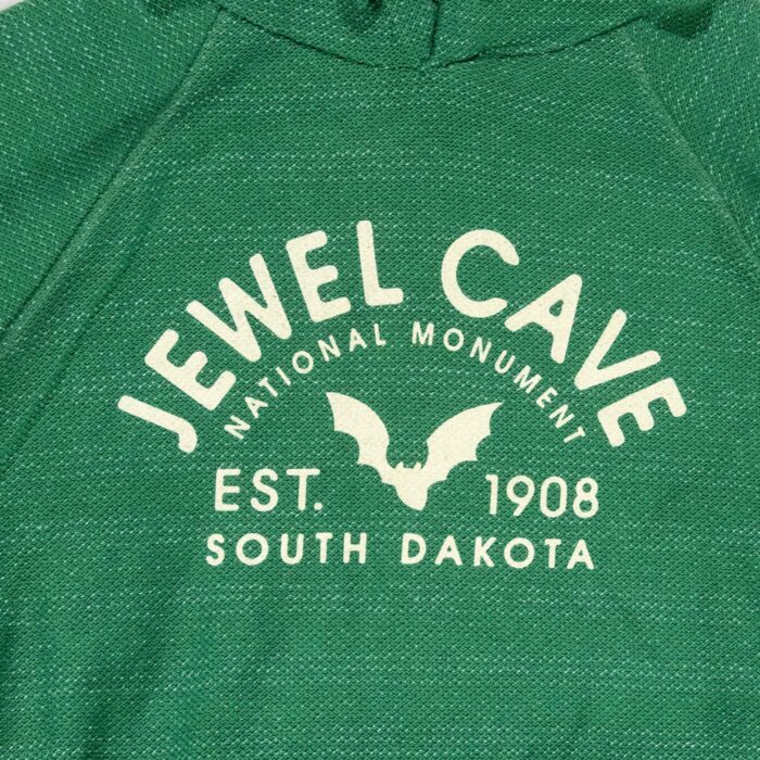 Close-up of the Jewel Cave National Monument front graphic, arched Jewel Cave lettering around a bat with EST. 1908 and South Dakota