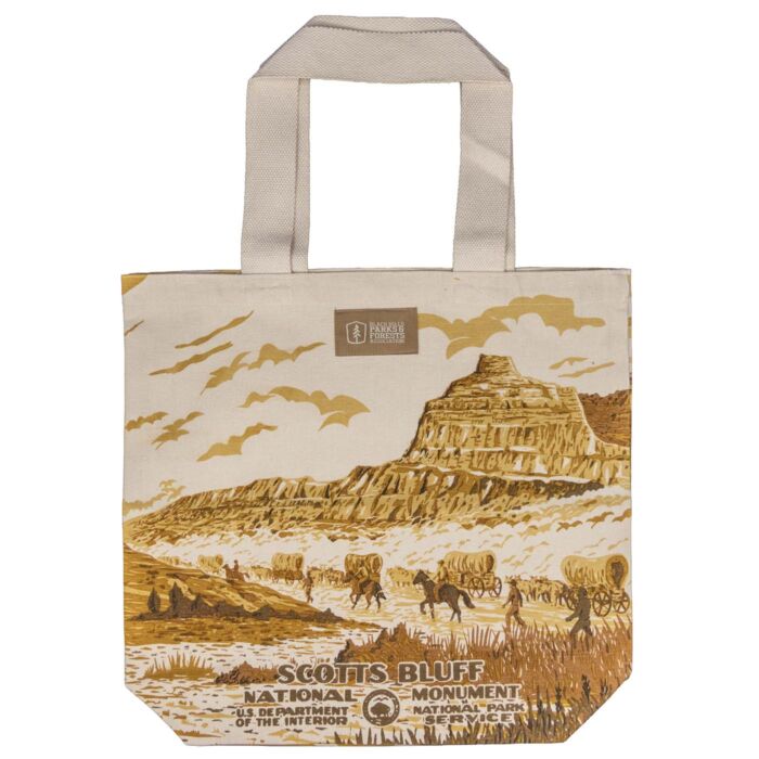Scotts Bluff National Monument canvas tote bag, front, with a WPA poster style wagon train scene below the bluff
