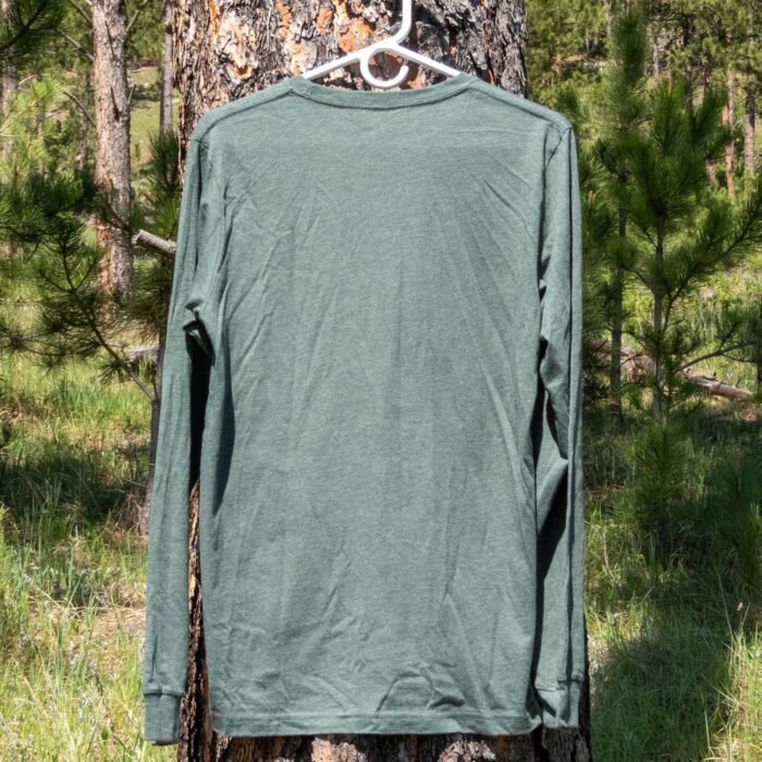 Back of the tee on a hanger outdoors against a pine trunk