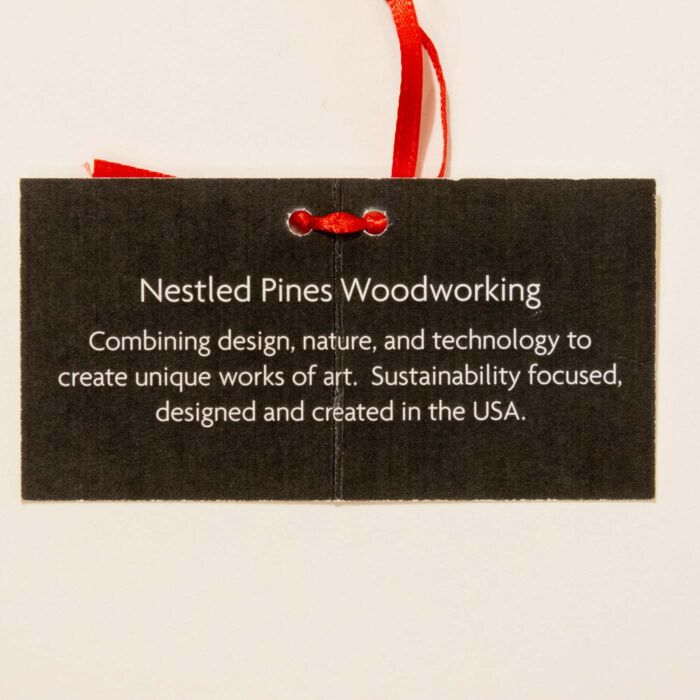 Nestled Pines Woodworking packaging describing the ornament as designed and created in the USA